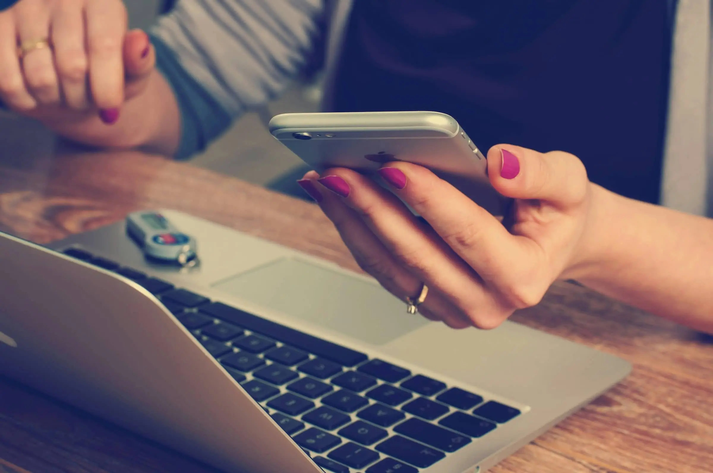 Person sitting at table using iPhone