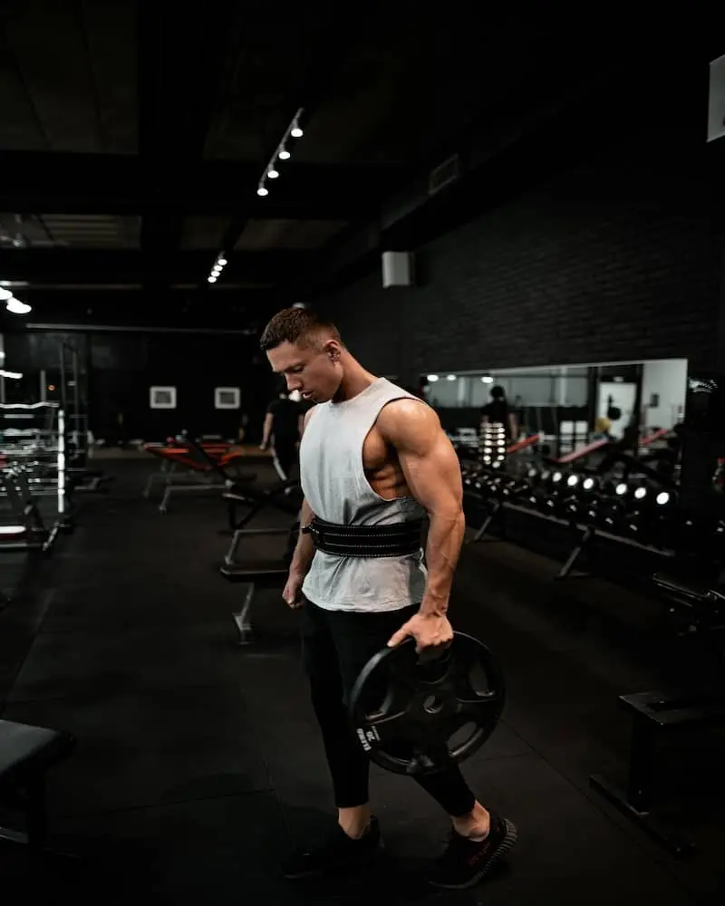 Man in White Tank Holding Bumper Plate